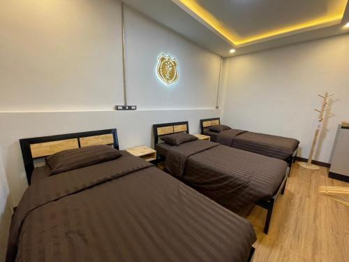 a room with three beds and a crest on the wall at Yaowarate Sport Club and Resort ไร่เยาวเรศ in Ban Mae Ho Phra