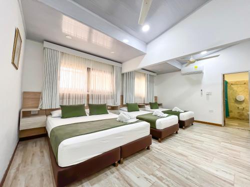 a bedroom with two beds and two ottomans at Hotel Camino Verde in Tolú