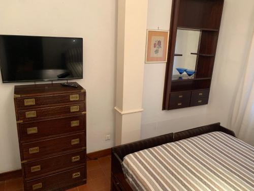 a bedroom with a bed and a dresser with a television at Villino a 300 mt dal mare - A solo un'ora di treno dal centro di Roma in Anzio