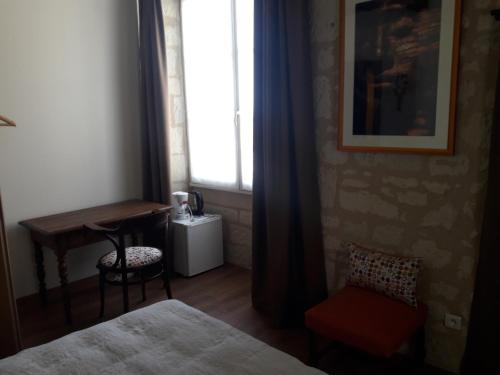 une chambre avec un lit, un bureau et une fenêtre dans l'établissement Le jardin des envies, à Candes-Saint-Martin