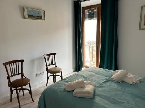a bedroom with a bed and two chairs and a window at La Bodeguita in Belmonte de Tajo