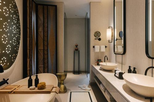 a bathroom with two sinks and a tub and a sink at Our Habitas Ras Abrouq in Dukhān