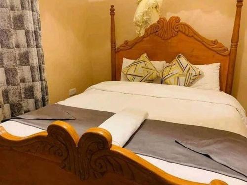 a bed with a wooden headboard in a bedroom at Villa Serene Hotel in Kitale
