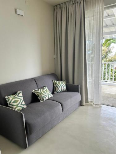 a gray couch with pillows in a living room at Blue Paradise Villa & Apartments in Blue Bay