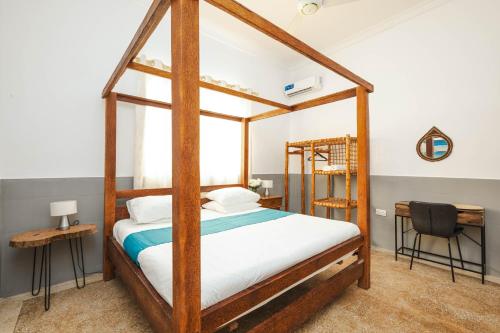 ein Schlafzimmer mit einem hölzernen Himmelbett mit weißer Bettwäsche in der Unterkunft Paje Holiday Home by Liv Zanzibar, central located in Paje
