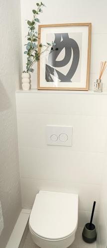 La salle de bains est pourvue de toilettes blanches avec une photo au-dessus. dans l'établissement Superbe T4 vue mer et etang, terrasse et parking, à Sète