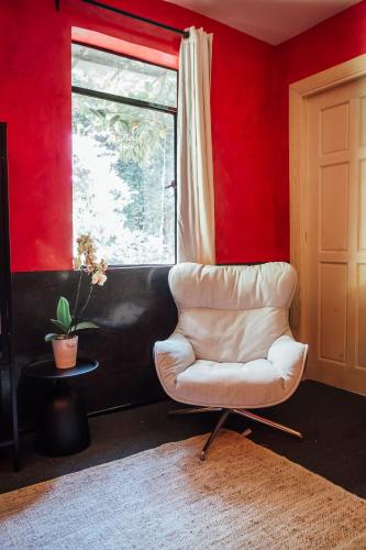 a white chair in a red room with a window at Maison du comte in Mexico City