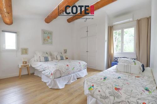 deux lits dans une chambre aux murs blancs et au parquet dans l'établissement Le Verdon, à Martigues