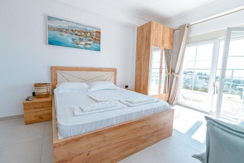 a bedroom with a large bed and a large window at Kotarja Apartments in Dhërmi