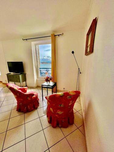 a living room with two red chairs and a window at La Langouste ROUGE in Camaret-sur-Mer