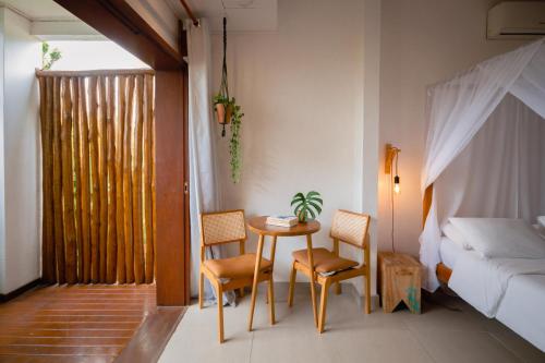 a room with a table and chairs and a bed at Villa Estrela Bungalow in Itacaré