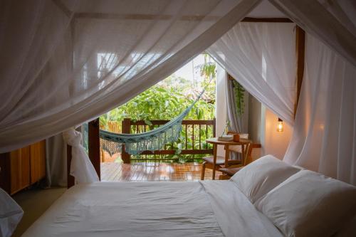 a bedroom with a bed and a hammock on a porch at Villa Estrela Bungalow in Itacaré
