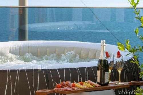 a bottle of champagne and a plate of food next to a bath tub at Magic Sea View - Apartments Rina in Karlobag