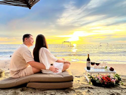 a couple sitting on the beach watching the sunset at Hotel Camino Verde in Tolú