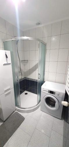 a washing machine in a bathroom with a shower at Apartament Chłodna 14 in Suwałki