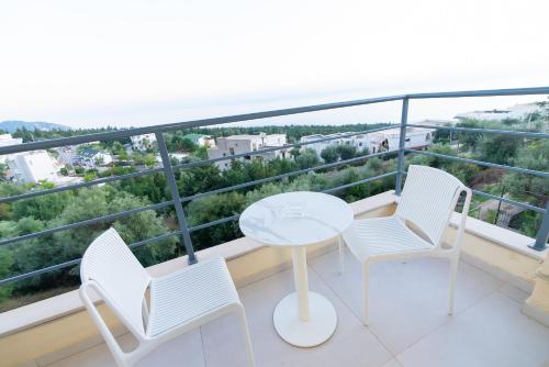 a balcony with white chairs and a table and a view at Kotarja Apartments in Dhërmi