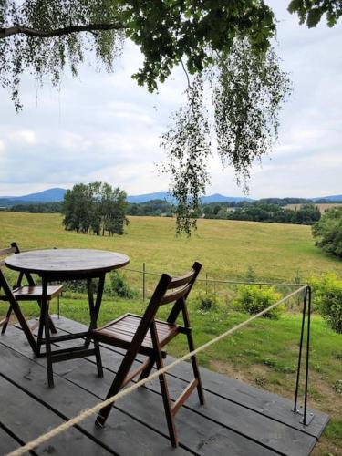 a table and a bench on a deck with a field at Domeček pohoda maringotka Máňa in Liberec