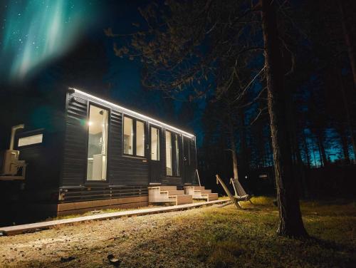 アカスロンポロにあるLapland Riverside, Landscape Cabin 8, KUUKKELI, Ylläs, Tiny Home with Sauna, Fireplace, Terrace, BBQ, Wifi, Ski, Fishing, Pets OKの夜の小屋