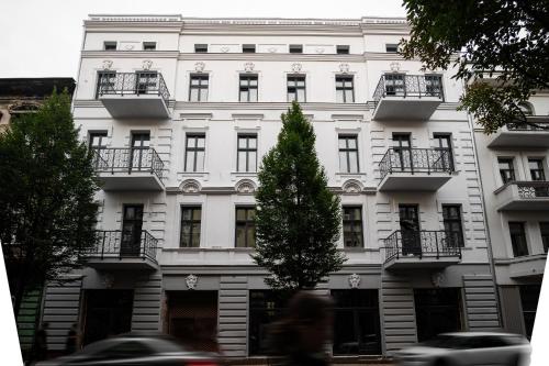 un edificio bianco con balconi e un albero di fronte ad esso di DREAM APARTMENTS - Wschodnia 34 a Łódź