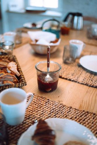 a wooden table topped with cups of coffee and food at Chambre tout confort à l'Héritier - au coeur du Tarn in Marzens