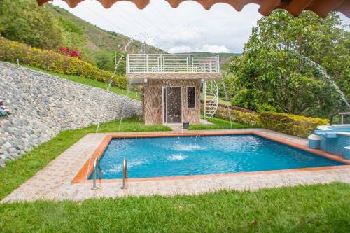 a swimming pool in the grass next to a waterfall at Finca Las Gaviotas - Mulaló, Yumbo in Yumbo