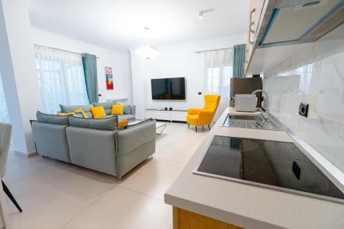 a kitchen and living room with a couch and a tv at Kotarja Apartments in Dhërmi