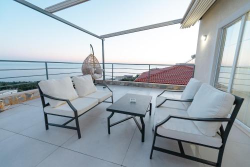 a balcony with two chairs and a table on a roof at Kotarja Apartments in Dhërmi