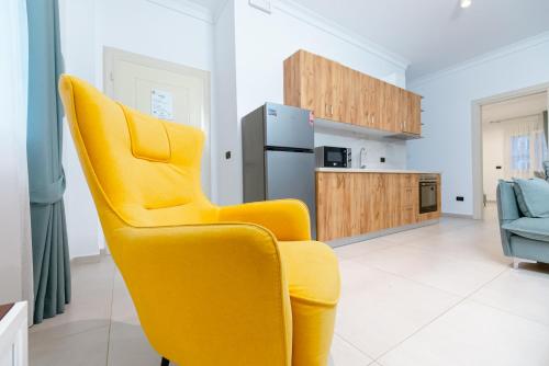 a yellow chair in a kitchen with a refrigerator at Kotarja Apartments in Dhërmi