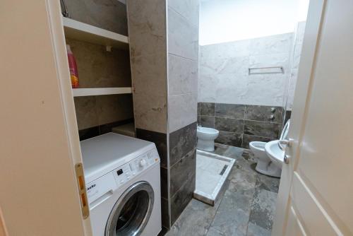 a laundry room with a washer and a toilet at Kotarja Apartments in Dhërmi