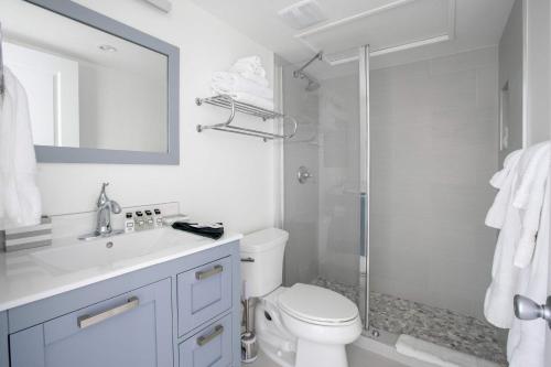 a white bathroom with a toilet and a shower at Beach Living at Plantation Village BLGS in George Town