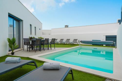 a swimming pool in a yard with a table and chairs at Villa Lola luxury villa with private pool and jacuzzi in Mariquiteira