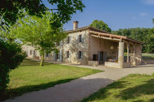 an old stone house with a tree in front of it at Chambre tout confort à l'Héritier - au coeur du Tarn in Marzens