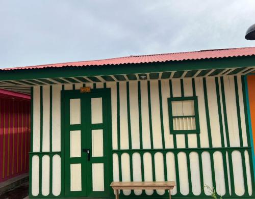 a building with a green door and a bench in front at El Agrado Restaurante Cabañas in Líbano