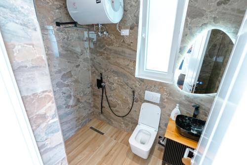 a bathroom with a toilet and a sink and a mirror at Kotarja Apartments in Dhërmi