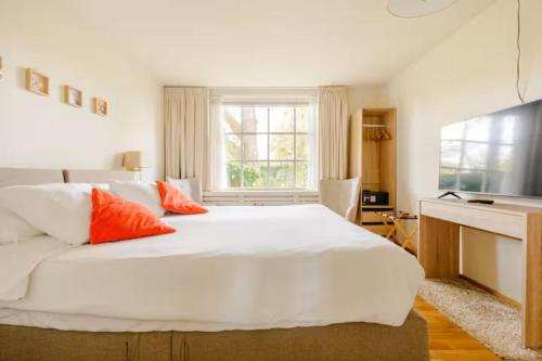a bedroom with a large white bed with orange pillows at Bed and Breakfast De Haen - Privé-appartementen van 43 of 60 m2 met tweepersoons bubbelbad - Finse sauna - in westvleugel van luxe villa in Oss