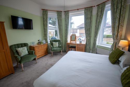 a bedroom with a bed and two chairs and a desk at Westbury Lodge in Shanklin