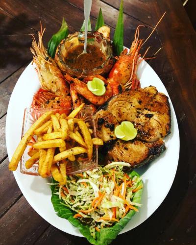 a plate of food with shrimp and french fries and salad at Oruwa Turtle Beach Villa in Kosgoda