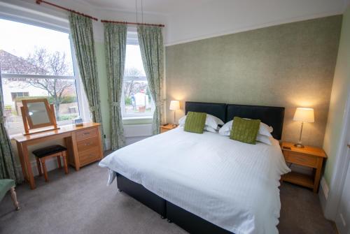 a bedroom with a bed and a desk and a mirror at Westbury Lodge in Shanklin