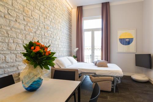 Cette chambre comprend 2 lits et une table ornée d'un vase de fleurs. dans l'établissement Residenza Trinità Maggiore, à Naples