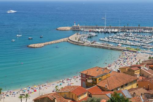 une plage avec une foule de gens et de bateaux dans l'établissement Au vieux château, atypique vue mer, à Menton