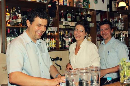 three people standing at a bar with a woman at Hotel Kaiser Bridge in Benitses
