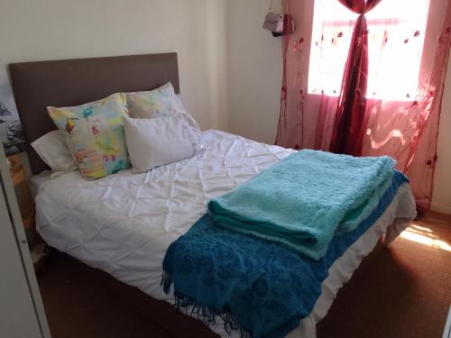 un lit avec des draps et des oreillers blancs et une fenêtre dans l'établissement Kenda house, au Cap