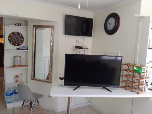 Une télévision à écran plat est installée au-dessus d'une table blanche. dans l'établissement Kenda house, au Cap
