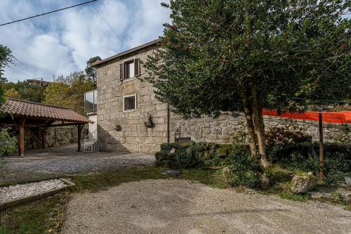 a stone house with a tree in front of it at Quinta de São Martinho Visconde do Penedo in Soengas