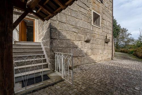 a stone building with a staircase next to a door at Quinta de São Martinho Visconde do Penedo in Soengas