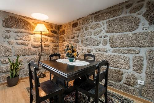 a dining room with a table and chairs and a stone wall at Quinta de São Martinho Visconde do Penedo in Soengas
