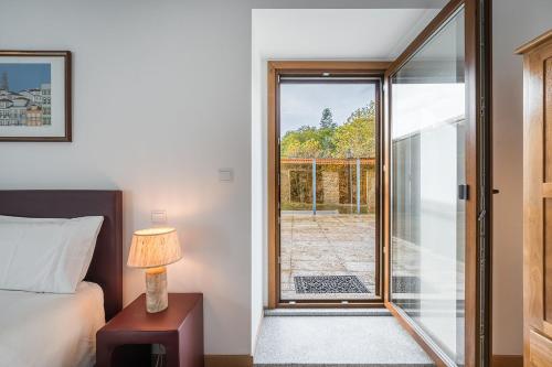 a bedroom with a bed and a door to a patio at Quinta de São Martinho Visconde do Penedo in Soengas