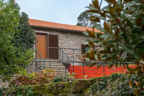 a small stone house with a red staircase in front of it at Quinta de São Martinho Visconde do Penedo in Soengas