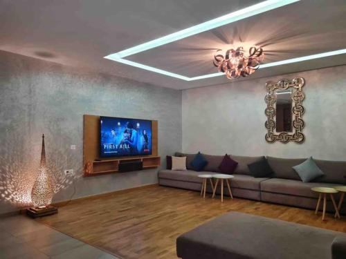 a living room with a couch and a flat screen tv at Superbe Villa ,Piscine,Accès plage,Zone balnéaire in Tamraght Ouzdar