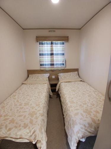 two beds in a small room with a window at Gold Plus Caravan in Dymchurch
